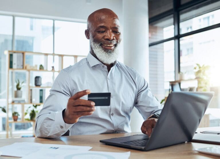 Happy black man, business credit card and laptop for ecommerce, finance and accounting in office. M