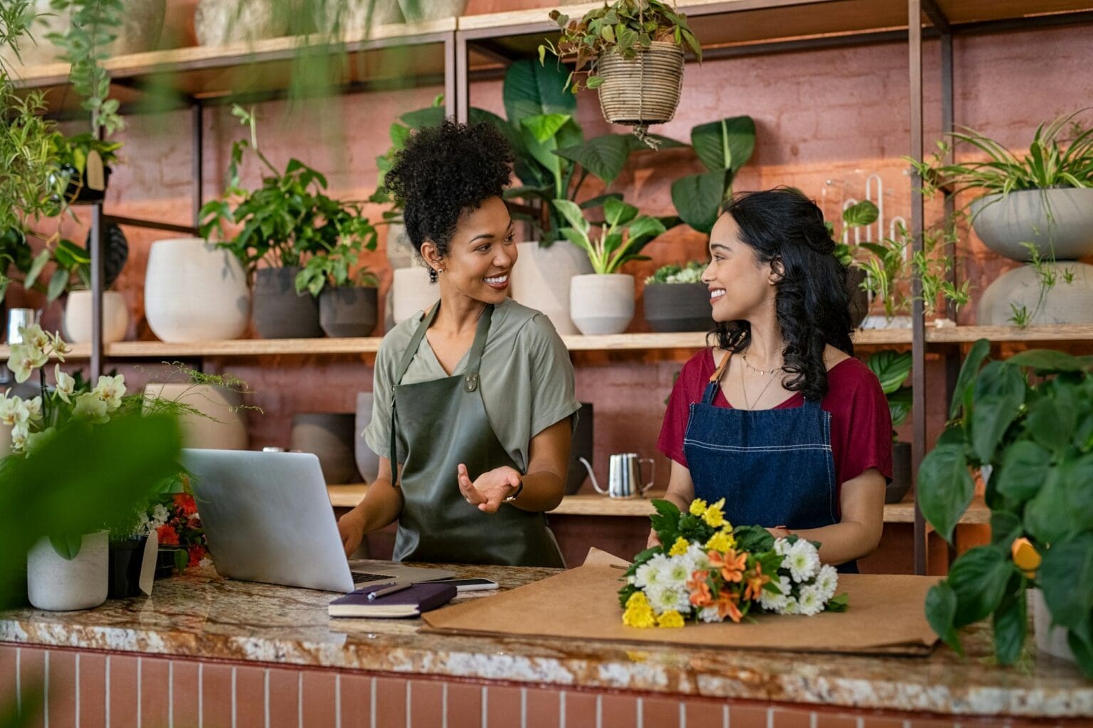 Two smiling women working at florist shop